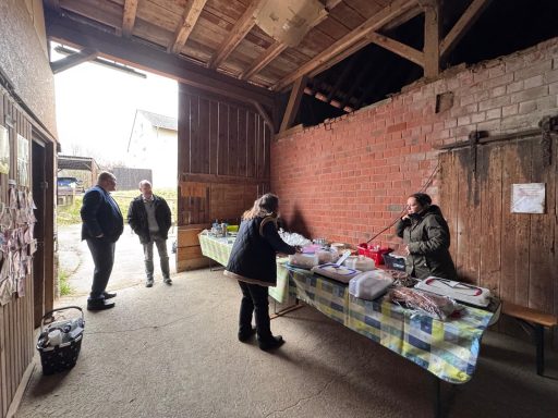 Markt im Innenraum mit Ständen und Besuchern, die lokale Produkte anbieten.